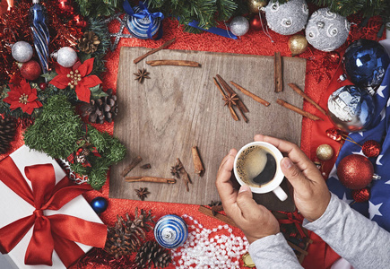 男手与一杯冬季饮料在红色木桌上与圣诞礼物和装饰, 新年的背景, 平躺。具有可用文本空间的布局