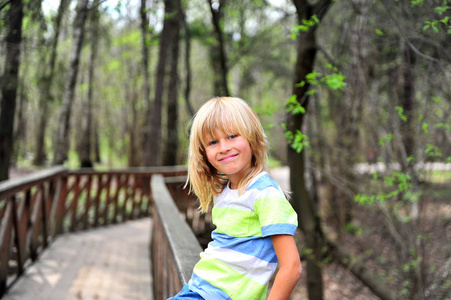 坐在森林篱笆上的微笑男孩