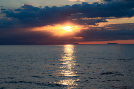 云彩背后的夕阳与海面上的太阳倒影在水面上