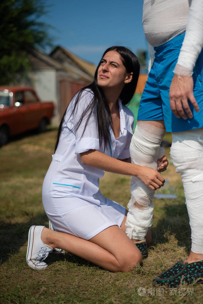 一个年轻的护士在乡下把病人的腿包扎在室外