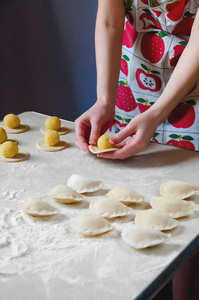 妇女手造型饺子与土豆在白色背景。乌克兰传统食品