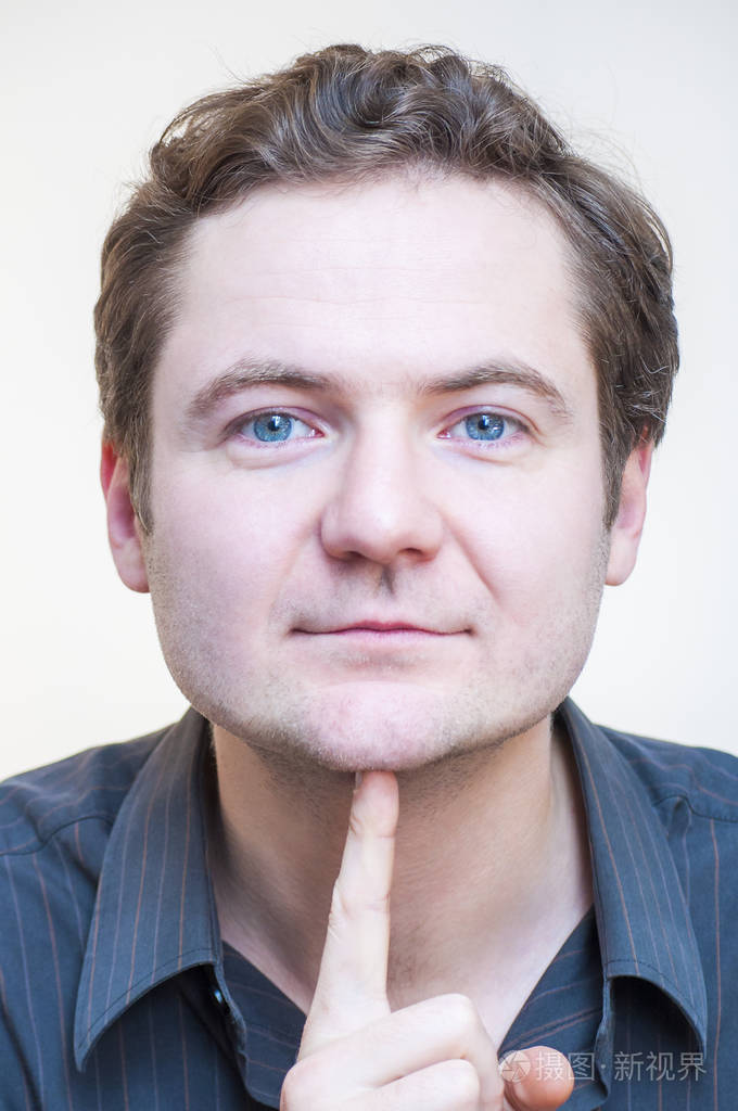 年轻的白种人种族的肖像蓝眼睛男子点在他的下巴上的白色背景.