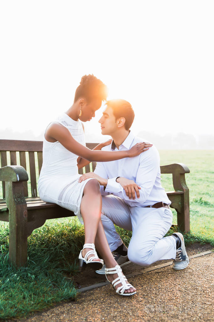 年轻浪漫的情侣面对面地坐在阳光下看着户外