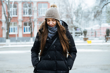 在寒冷的城市里, 戴着一顶暖和的帽子散步的漂亮女孩