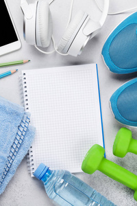 健身概念背景与运动鞋, 哑铃, 水瓶, 智能手机和耳机。使用记事本查看文本的顶部视图