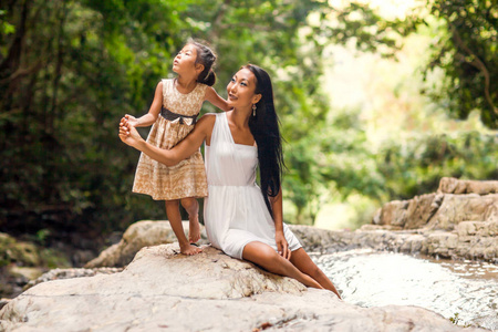 快乐的母亲与她的女儿在热带附近的瀑布。母亲节