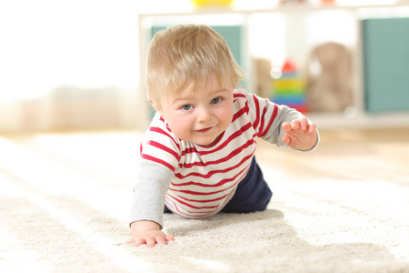婴孩爬行对照相机在地板上