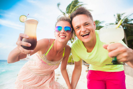 愉快的年轻夫妇与鸡尾酒在海滩乐趣