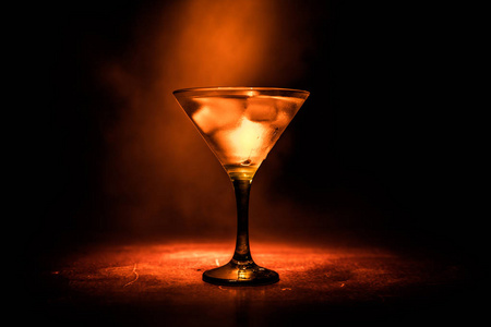 火马提尼的概念。一杯著名的鸡尾酒马提尼在大火中燃烧在黑暗色调的雾背景。选择性聚焦
