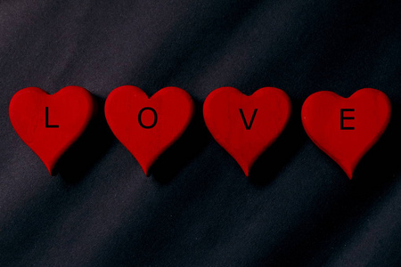 红色木制手工心脏符号的顶部, 用黑色背景写着 爱。黑暗, 优雅和奢华的背景。情人节主题