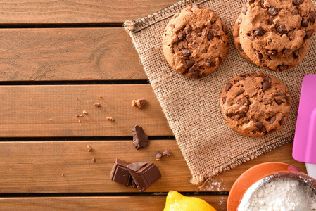 自制饼干, 配有巧克力薯片, 木质板条桌上有配料的质朴厨房。水平组合。顶部视图