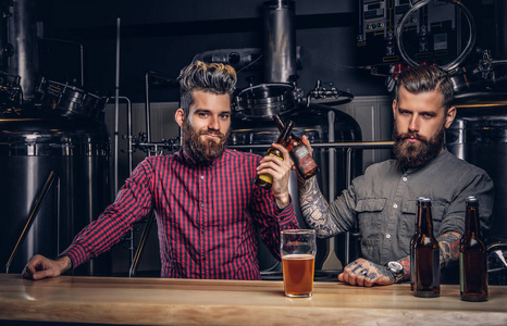 两个时尚的胡子嬉皮士朋友一起喝啤酒在独立酿酒厂