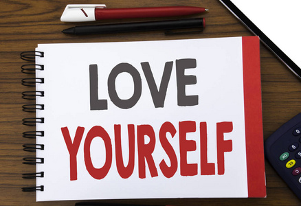 手写文字显示爱你自己。商业概念写作为正面口号为您写在记事本笔记纸, 木背景在办公室看法与铅笔标记计算器