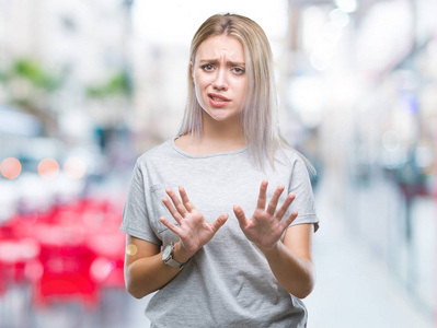 年轻的金发女人在孤立的背景下反感表达, 不高兴和害怕做厌恶的脸, 因为反感反应。举手。恼人的概念