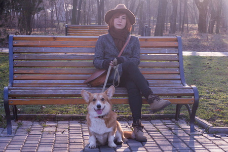 公园里戴着帽子的少妇带着可爱的犬狗, 阳光明媚的秋日