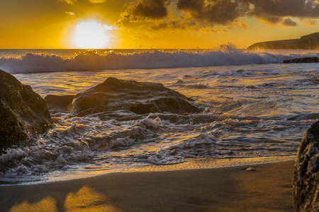 日落在富埃特文图拉岛民海滩与熔岩岩石, 乌云和小波浪