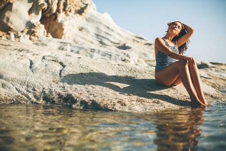 年轻漂亮的女人，坐在海边岩石上