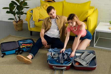 年轻夫妇包装手提箱和准备一起度假