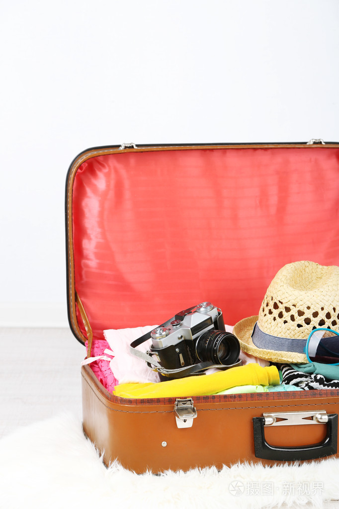 女性的衣服和照片相机在浅色背景的旧行李箱