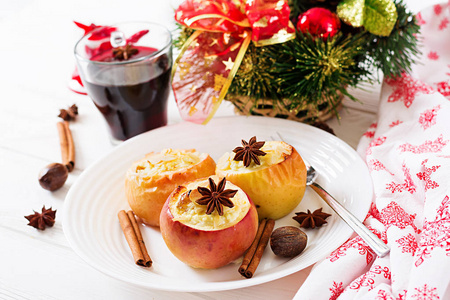 在餐桌上用葡萄酒杯和叉子在白色盘子上, 用小干酪葡萄干和杏仁填充烤苹果。圣诞食品甜点