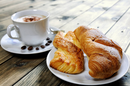 传统的意大利早餐与卡布奇诺和牛角面包在一个质朴的木桌上照片