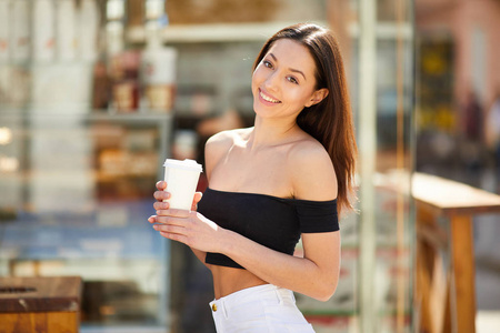 黑发女孩站在街上看着相机, 并烘干她的 d