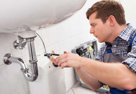 年轻的水管工在浴室中修复一个接收器