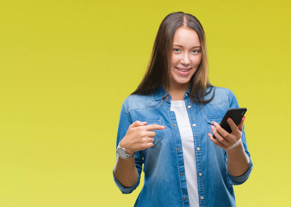 年轻美丽的白人妇女短信发送消息使用智能手机在孤立的背景与惊讶的脸指向自己的手指