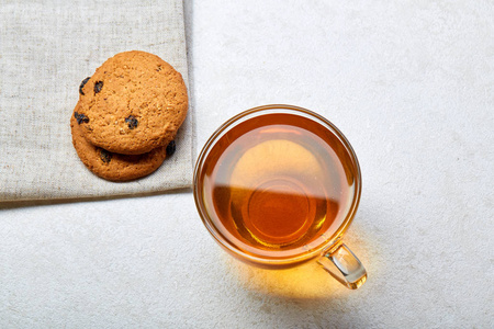 顶部视图关闭透明杯中的茶叶图片与饼干饼干在白色背景的棉餐巾上