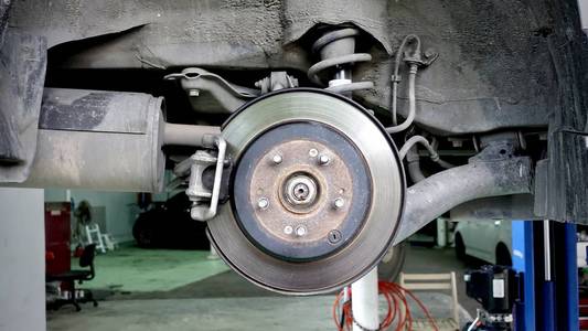 波纹车排气系统在浅景深和盘式制动器的车辆维修, 在新轮胎更换过程中。汽车刹车修理在车库。特写