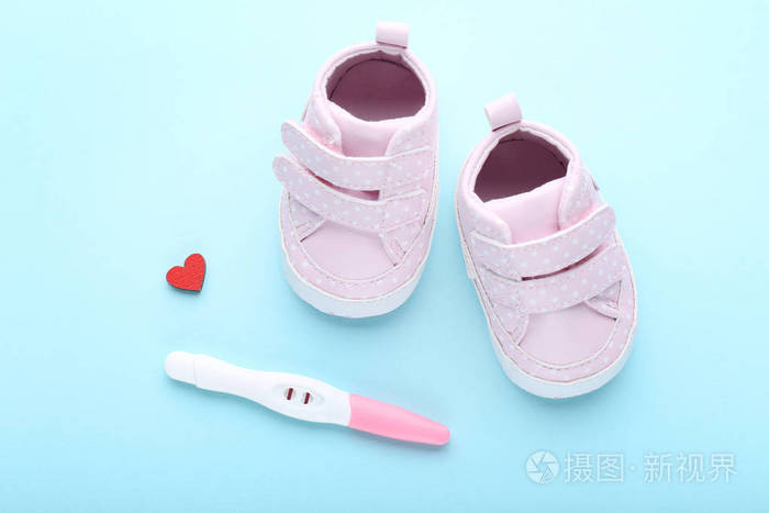 怀孕测试与婴儿靴在蓝色背景
