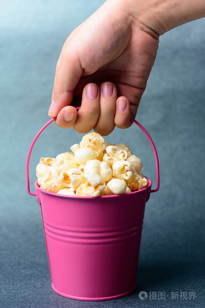手拿着一个粉红色的焦糖爆米花桶