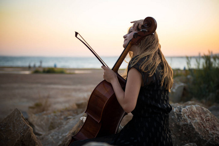 年轻美丽的女孩与她的大提琴在外面