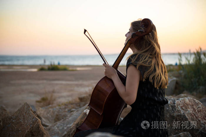 年轻美丽的女孩与她的大提琴在外面