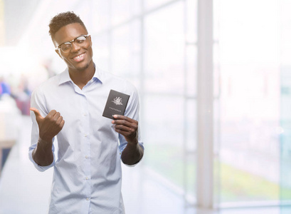 年轻的非洲裔美国人持有澳大利亚护照指向用手和手指与快乐的脸微笑