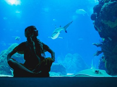 女孩看鱼通过玻璃在水族馆