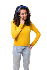 年轻的女孩与黄色毛衣和蓝色头巾在她的头站立, 并期待前面打开眼睛与手指在孤立的白色背景
