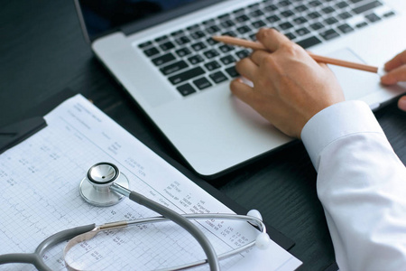 医生使用笔记本电脑在办公桌上使用听诊器的医疗检查报告