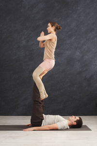 年轻夫妇在垫子上练习 acroyoga