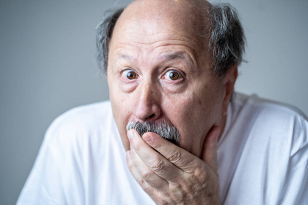 嘴露出惊讶的表情特写一位害怕的老人的肖像,在人类情感中表达恐惧,在