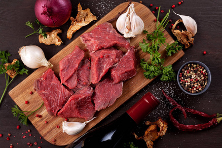 生鲜肉一瓶葡萄酒和时令秋季有机蔬菜在木板上准备烹调