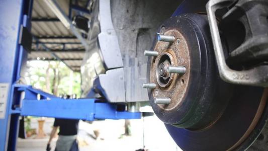 波纹车排气系统在浅景深和盘式制动器的车辆维修, 在新轮胎更换过程中。汽车刹车修理在车库。特写