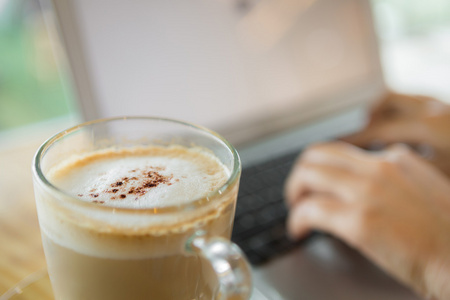 咖啡和在笔记本电脑键盘上打字的手的特写