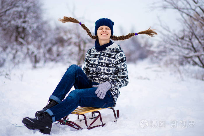 快乐的年轻女子在雪地里玩雪橇