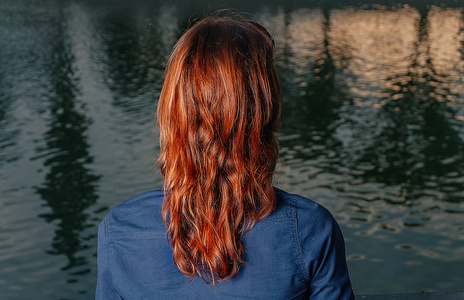 红头发的女孩看着河与夜城反射