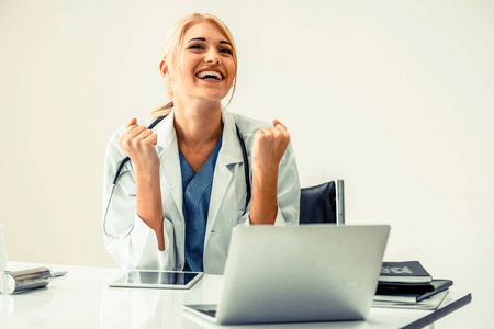 快乐成功的女医生在医院或医疗机构工作时感觉很愉快, 在办公桌上做医疗报告。成功理念