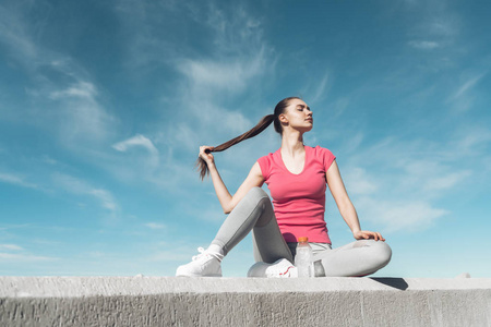 自信坚强的女孩穿着运动衣坐在户外, 获得力量和精力训练照片