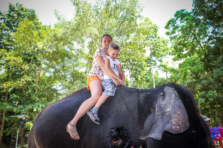 泰国苏梅岛,2013 年 4 月 4 日母亲和儿子骑在大象上照片