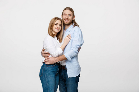 欢快的年轻夫妇的肖像站立和拥抱在孤立的白色背景