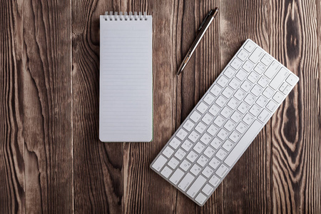 木制桌面上的白色记事本和电脑键盘